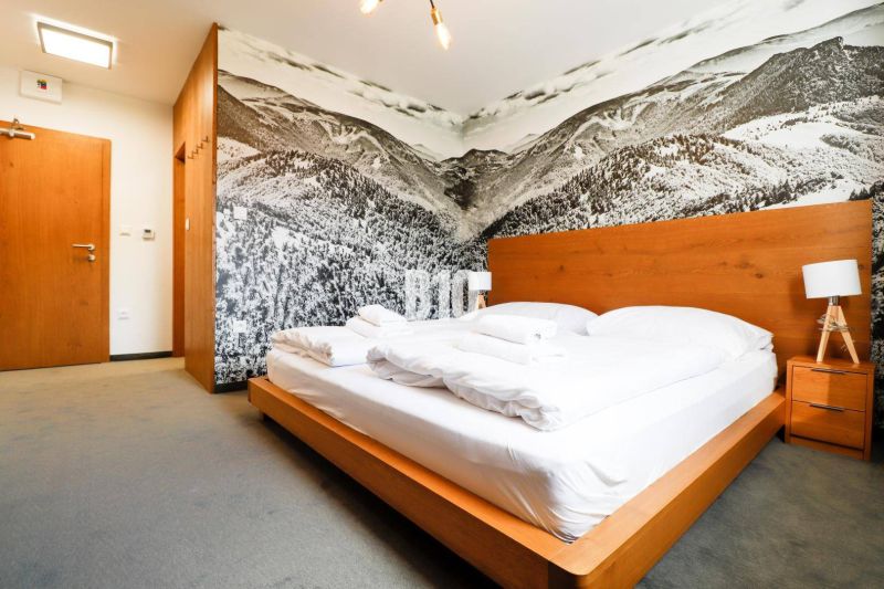 Ložnice s dřevěným nábytkem, velkým uměním na stěně a pohodlnou postelí v rekreačním apartmánu.