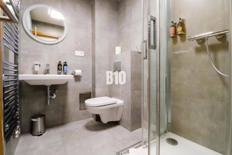 Koupelna rekreačního apartmánu se sprchovým koutem, toaletou a umyvadlem v elegantním designu.