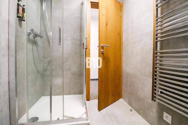 Koupelna se skleněným sprchovým koutem a žebříkovým radiátorem v Rekreačním apartmánu.