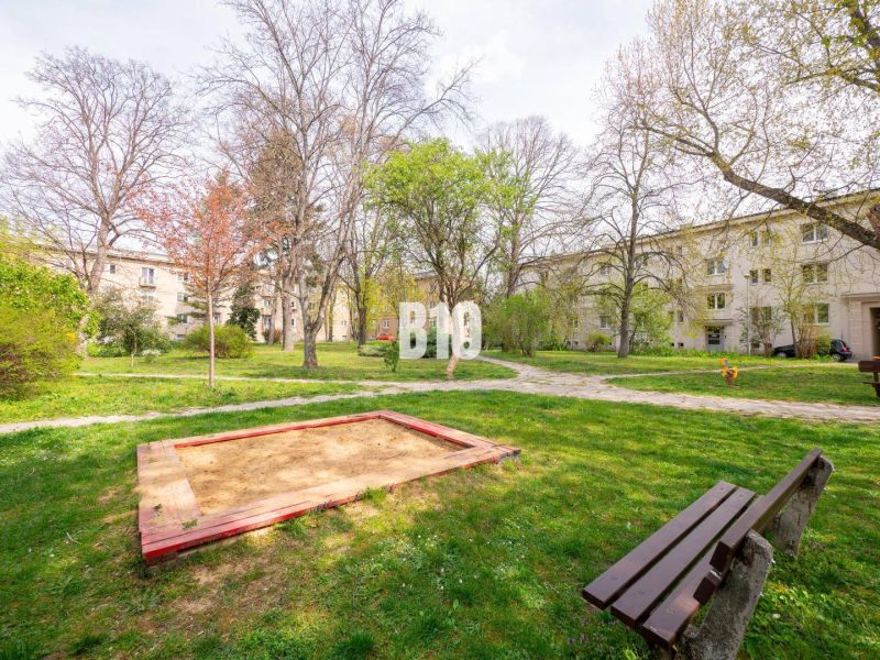 Dvorek v Nitře s dětským pískovištěm, lavičkami a okolními obytnými domy.