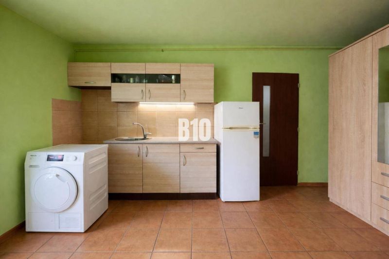 Kuchyně v rodinném domě s dřevěným dekorem nábytku, zelenými stěnami a dlažbou.