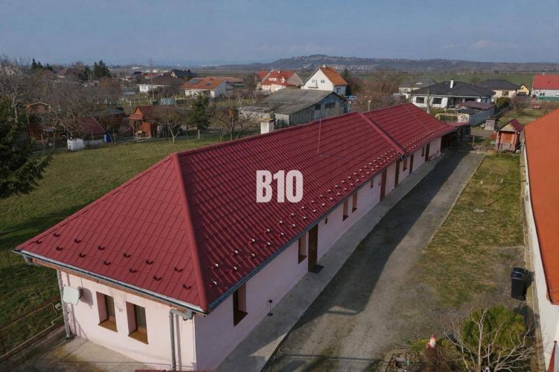 Rodinný dům v Levicích s dlouhou červenou střešní krytinou, obklopený zahradami.