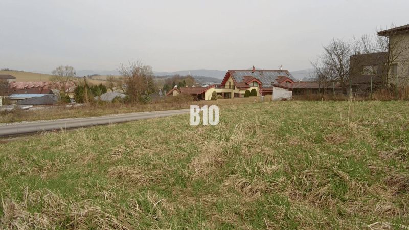 Pozemky - bydlení v obci Rosina, travnatý pozemek s okolím venkovských domů.