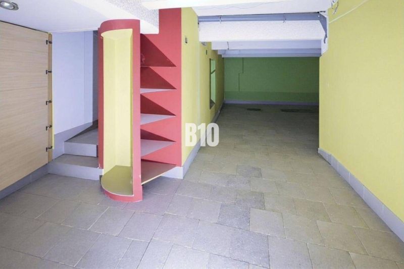 Interiér obchodních prostor s barevnými stěnami, regály a schody na dlažbě.