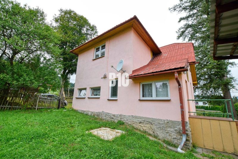 Rodinný dům v Makově s růžovou fasádou, zahrada a satelitní anténa na stěně.