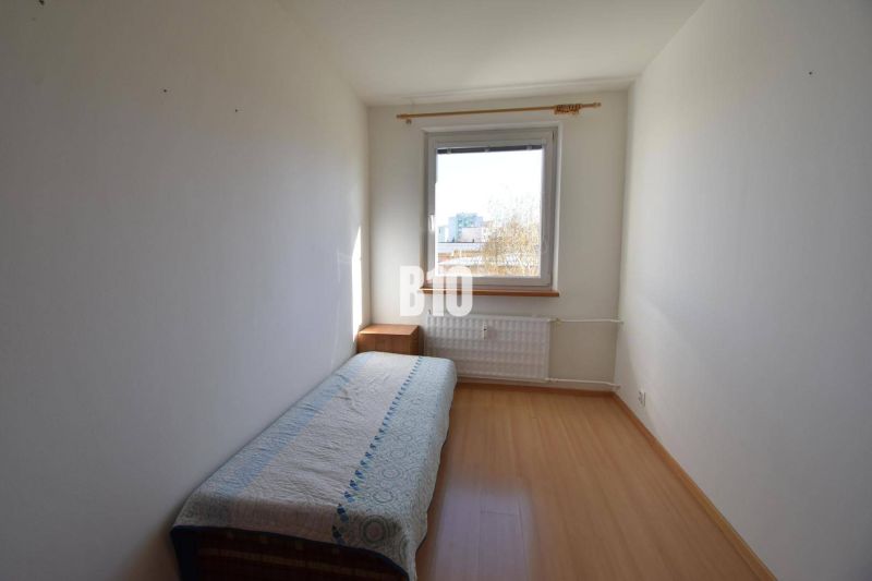 Pokoj s jednolůžkem, nočním stolkem a podlahou s dřevěným dekorem v bytě s 5 a více pokoji.