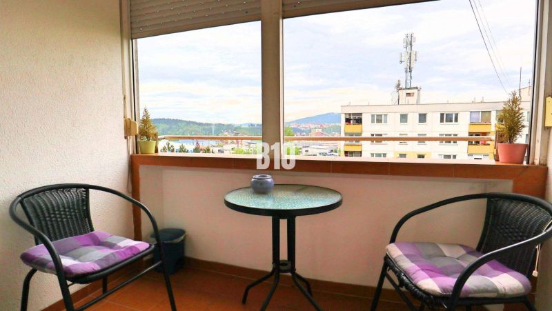 Balkon s výhledem na Žilinu ze 4pokojového bytu, dvě židle, stolek.