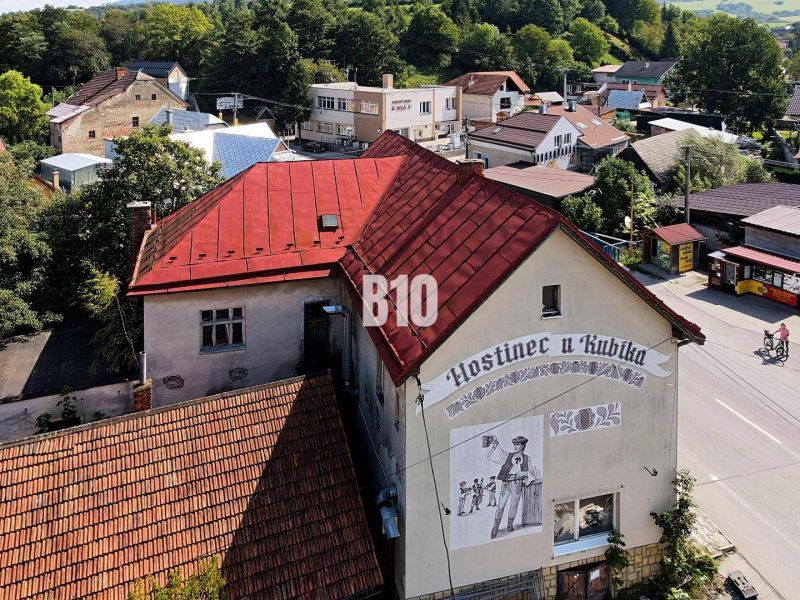 Hostinec v Bílé s červenou střechou a nástěnnou malbou muže s pivem.