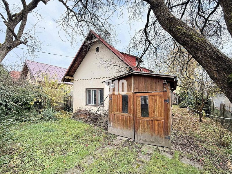Rodinný dům v Kotešové s dřevěným přístřeškem a zahradou na podzim.