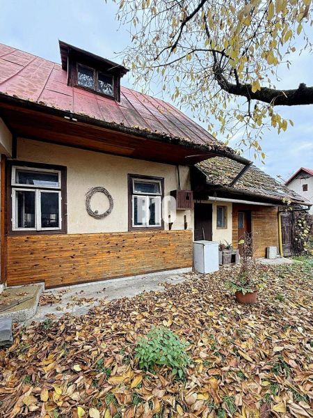 Rodinný dům v Kotešové se starým dřevěným opláštěním a padajícím listím na zahradě.