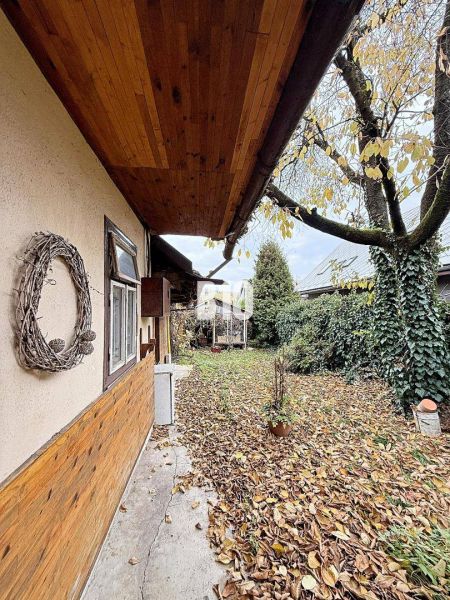 Rodinný dům v Kotešové se zahradou pokrytou listím a dřevěnými obklady na stěně.