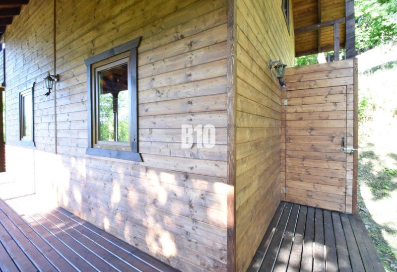 Dřevěná chata s terasou v Bytči, obklopená přírodou a slunečním světlem.