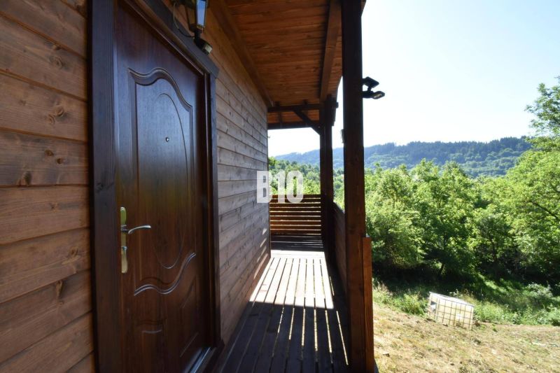 Chata u Bytče s dřevěnou terasou obklopená zelenou přírodou a lesy.