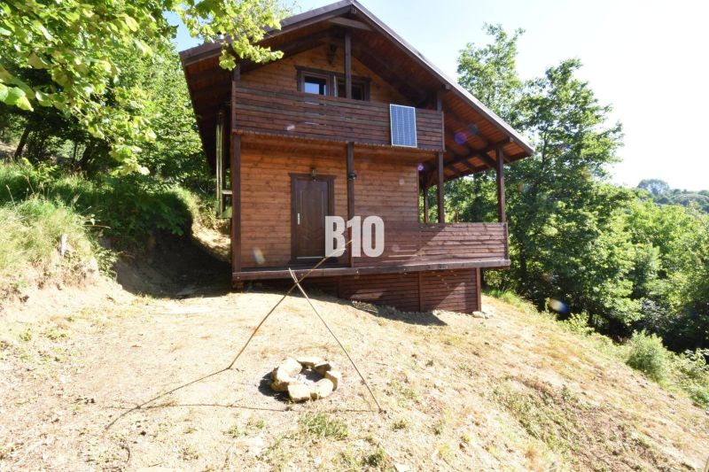Dřevěná chata v přírodě u Bytče, obklopená stromy a ohništěm.