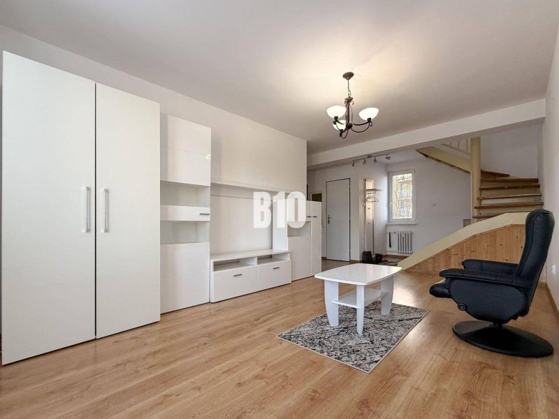 Obývací pokoj v rekreačním apartmánu s bílým nábytkem a podlahou s dřevěným dekorem.