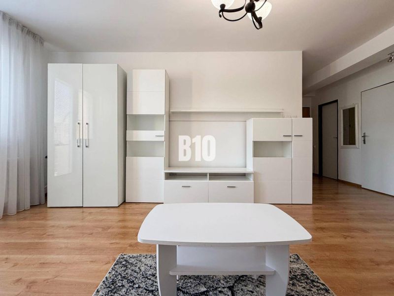 Interiér rekreačního apartmánu s bílým nábytkem a podlahou s dřevěným dekorem.