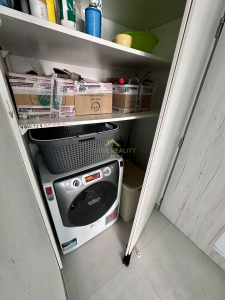 Úložný prostor v 3-pokojovém bytě s pračkou a regály.