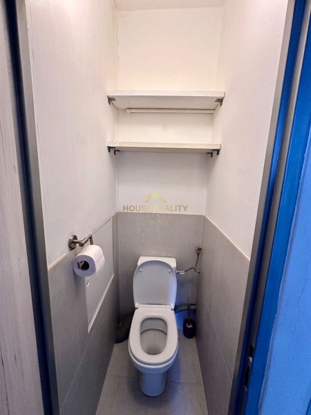 Toaleta v 3-pokojovém bytě se dvěma policemi na stěně.
