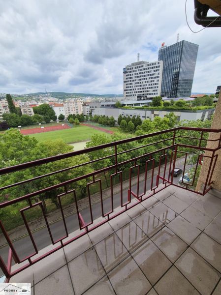 Výhled z balkonu na Jelačičově v Bratislavě - Ružinově s výškovou budovou v pozadí.