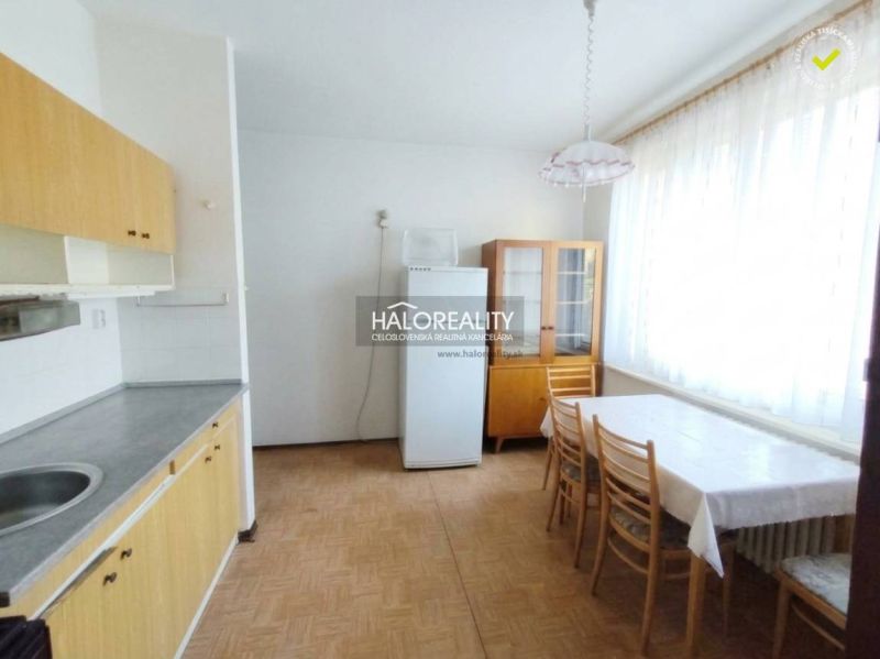 Kuchyně v 1-pokojovém bytě s jídelním stolem a podlahou s dřevěným dekorem.