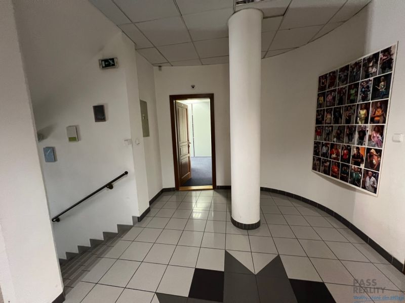 Chodba v kancelářích se schody a dekorací na stěně.
