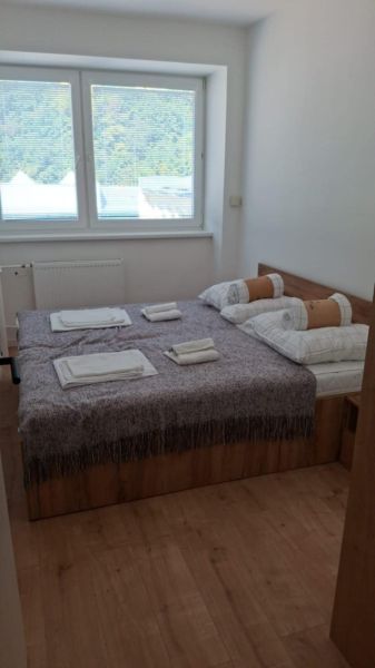 Ložnice s postelí a oknem, podlaha s dřevěným dekorem v dvoupokojovém bytě.