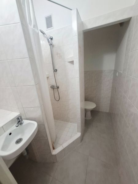 Koupelna s umyvadlem, sprchovým koutem a toaletou ve světlých obkladových barvách, 1-pokojový byt.