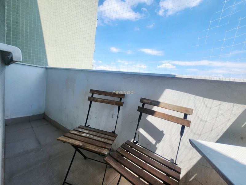 Balkon 3pokojového bytu se dvěma dřevěnými židlemi, modrou oblohou a ochrannou sítí.