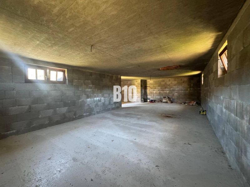 Interiér rozestavěné chaty s betonovými stěnami a podlahou.