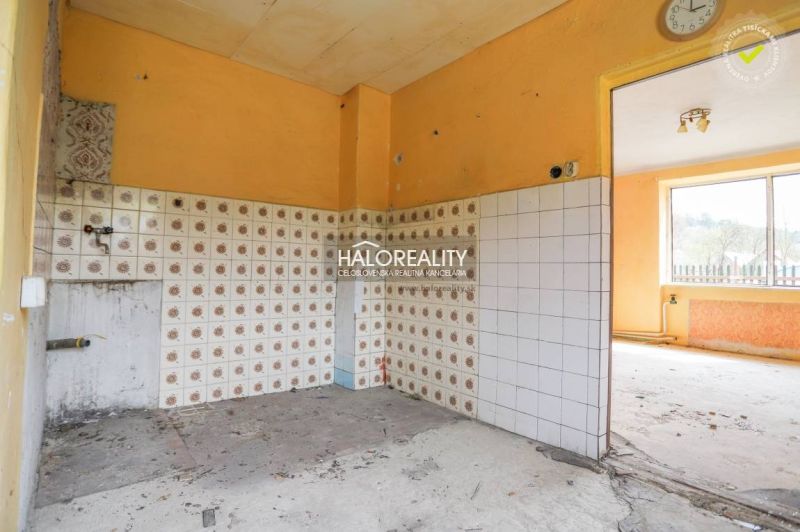 Kuchyně s oranžovými stěnami a vzorovanými obklady v rodinném domě.