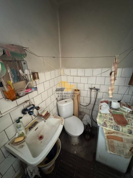 Koupelna v rodinném domě s umyvadlem, toaletou a starou pračkou.
