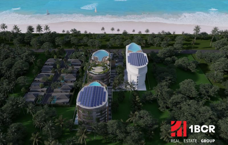 Plážová výstavba bytů v Phuketu s moderními budovami a bazény obklopenými palmami.