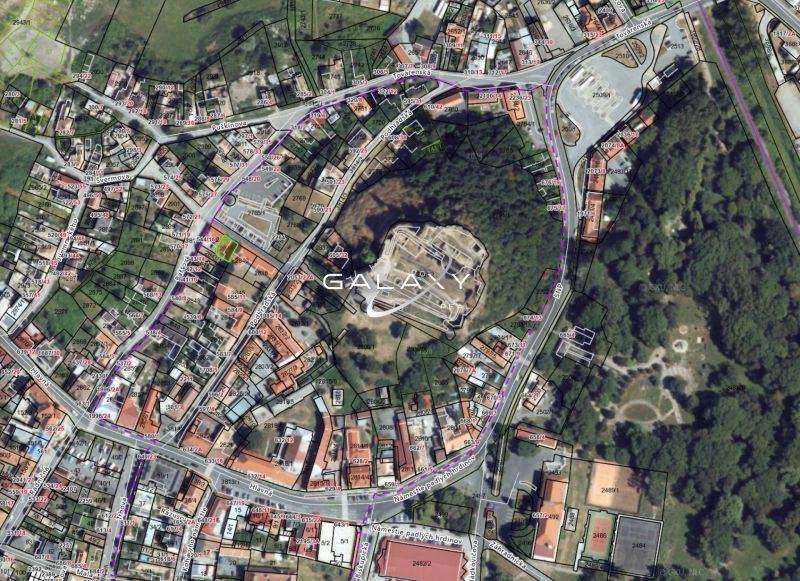 Letecký pohled na pozemky v historickém centru Fiľakova, obklopené budovami a zelení.
