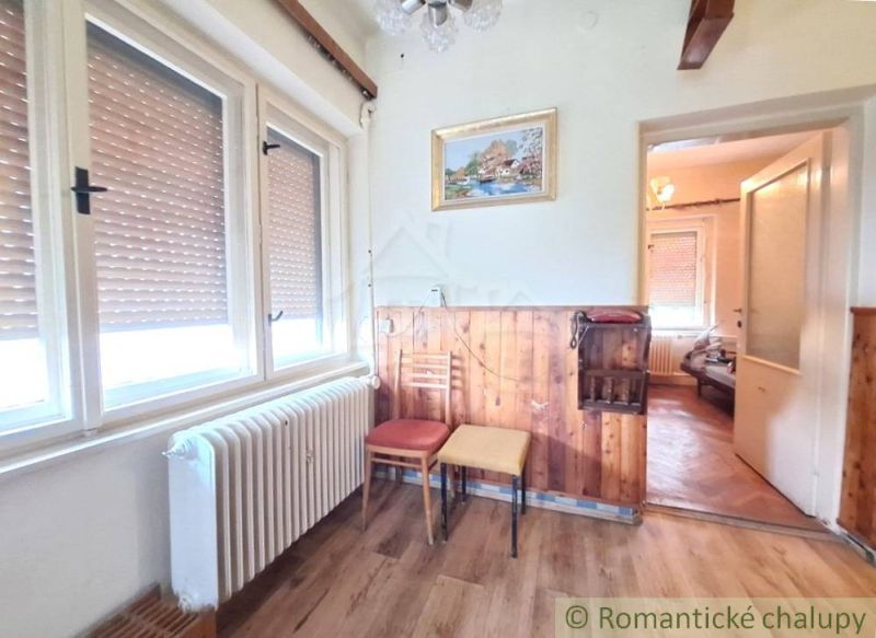 Interiér rodinného domu s podlahou s dřevěným dekorem a obrazem na stěně.