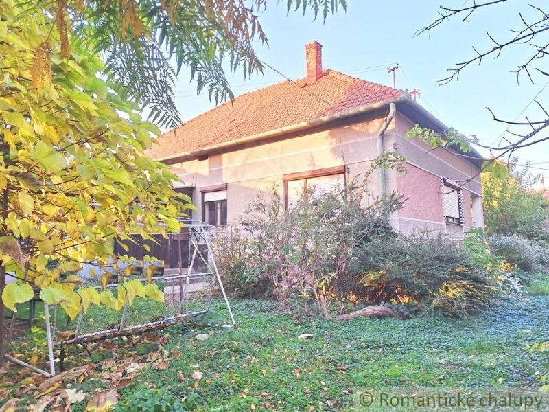 Rodinný dům v Gbelcích se zahradní houpačkou, obklopený zelení a keři.