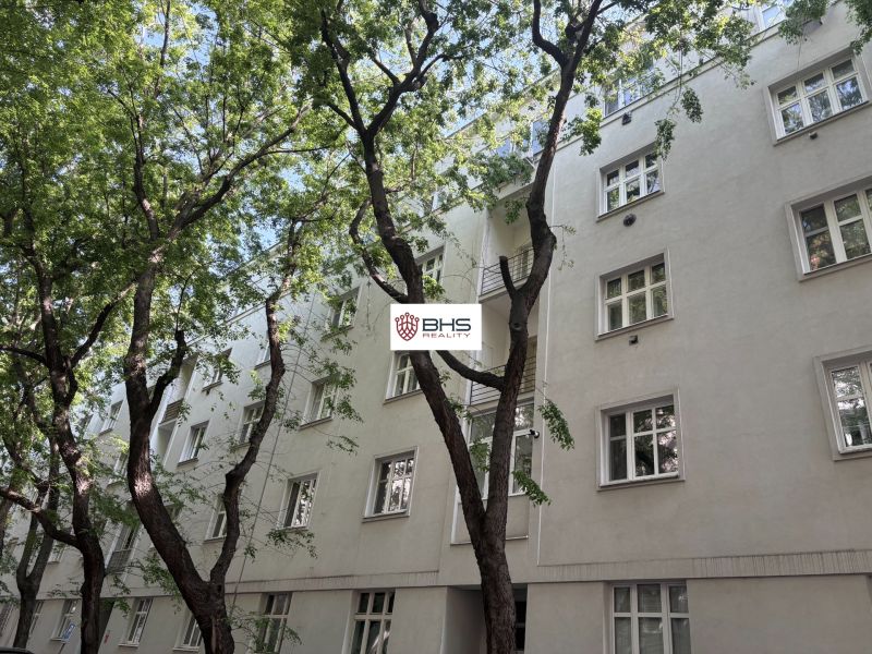 Bílý bytový dům na Dobrovského ulici v Bratislavě Starém Městě, obklopený zelení.