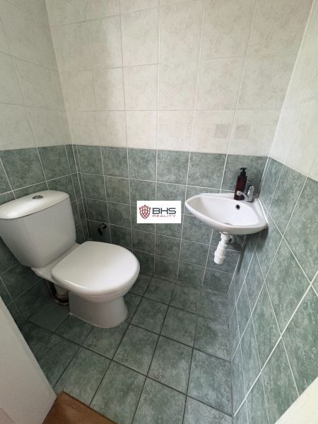 Toaleta s dlažbou a malým umyvadlem ve 2pokojovém bytě.