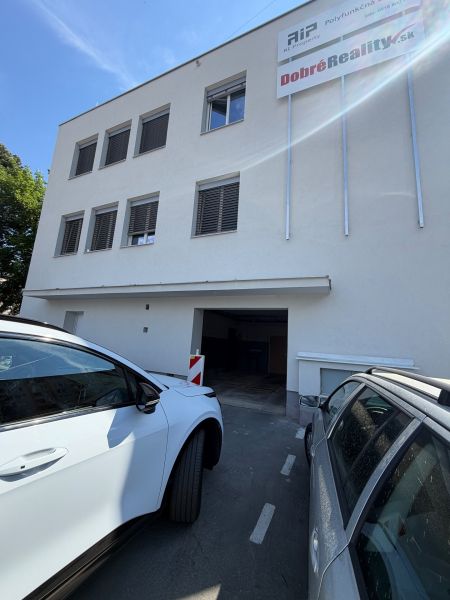 Budova s garážemi na Dlouhé ulici 3 v Prievidzi, zaparkovaná auta před budovou.