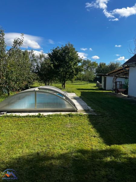 Rodinný dům v Čalovecké zahradě s bazénem pod obloukovým krytem a travnatou plochou.
