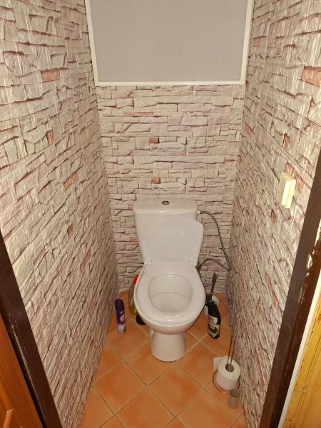 Koupelna s WC a stěnami s dekorem cihlové zdi v 2-pokojovém bytě.