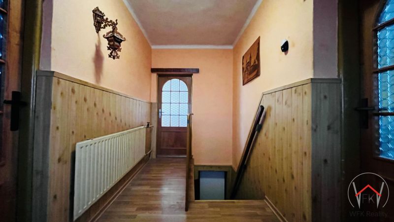 Chodba s dřevěným obkladem, podlahou s dřevěným dekorem a schodištěm v rodinném domě.