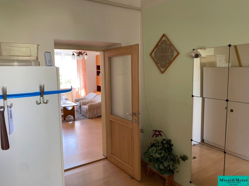 Interiér 2-pokojového bytu s podlahou s dřevěným dekorem, viditelná obývací místnost.