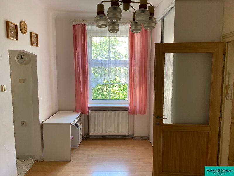 Pokoj s podlahou s dřevěným dekorem a růžovými závěsy v 2-pokojovém bytě.