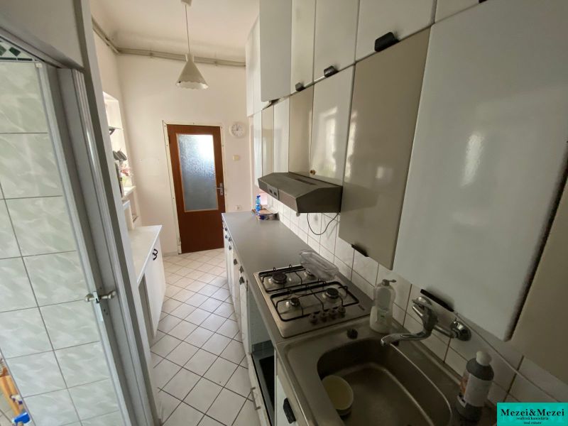 Kuchyně v 2-pokojovém bytě s bílými skříňkami a dlažbou na podlaze.