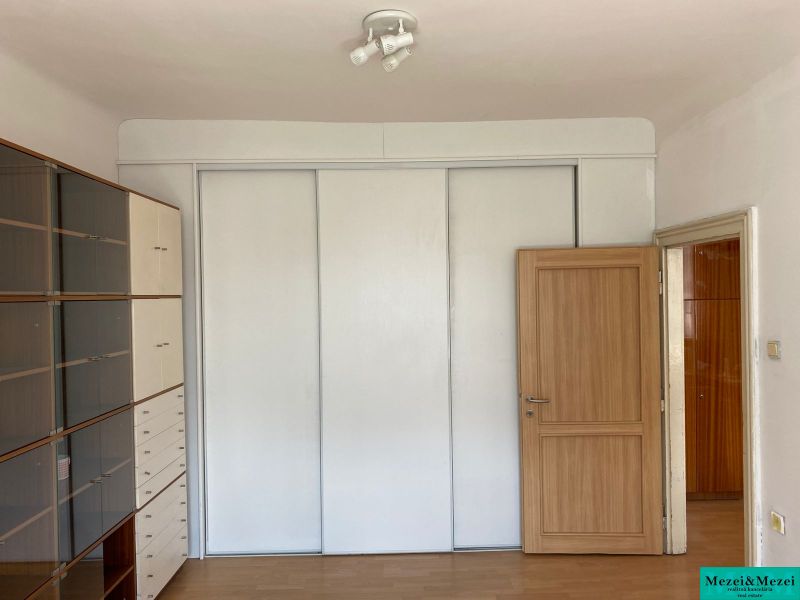 Interiér 2-pokojového bytu s bílou skříní a policovou sestavou, podlaha s dřevěným dekorem.