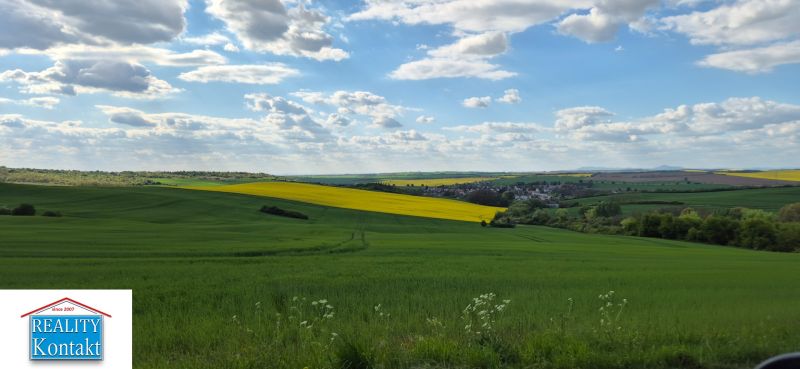 Vesnice nabízí úchvatný pohled na zelenou krajinu s modrou oblohou a oblaky.