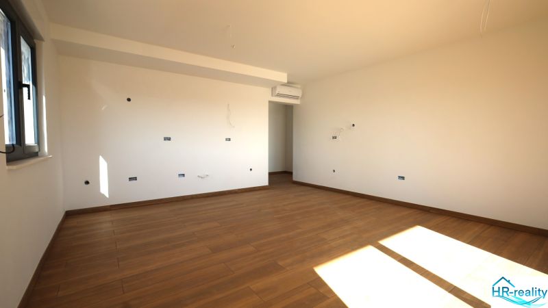 Světlá místnost s podlahou s dřevěným dekorem v rekreačním apartmánu.