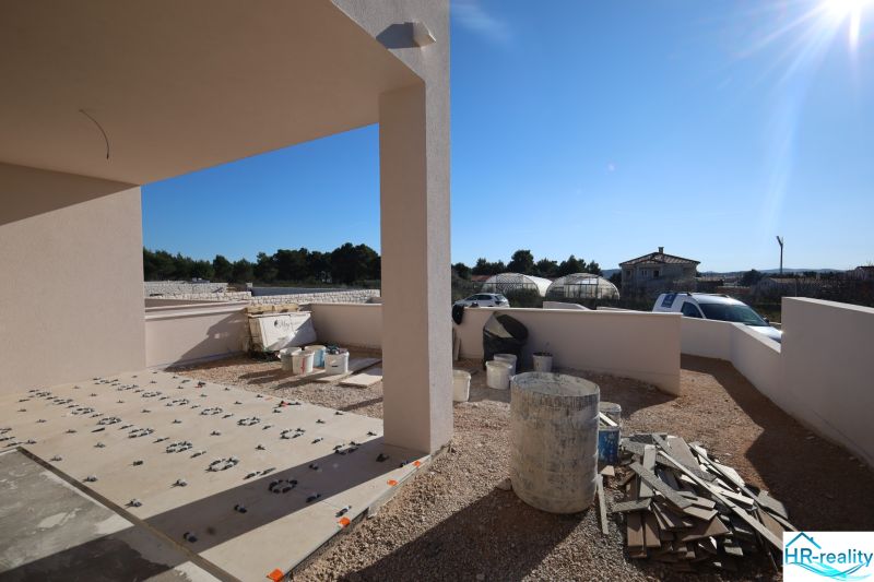 Stavební práce na terase rekreačního apartmánu ve Vodicích, slunečný den, viditelné nádoby a materiál.
