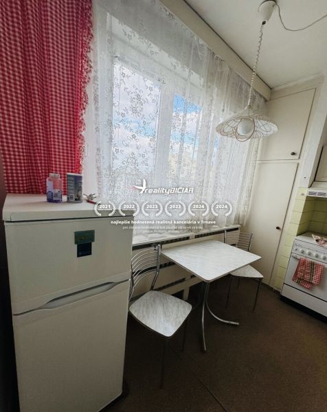 Kuchyně v 3-pokojovém bytě, s lednicí a stolem, záclony, červené kostkované závěsy.