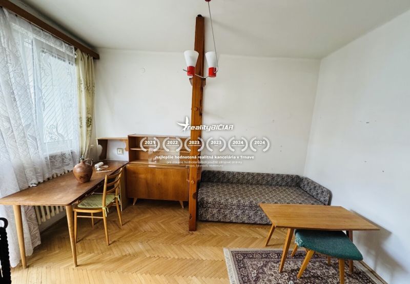 Pokoj v 3-pokojovém bytě s podlahou s dřevěným dekorem, nábytkem a dekorativními doplňky.
